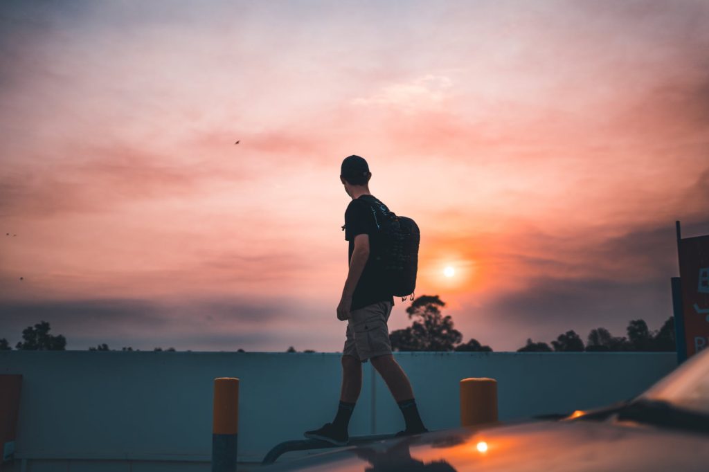 man walking on metal pipe near the road