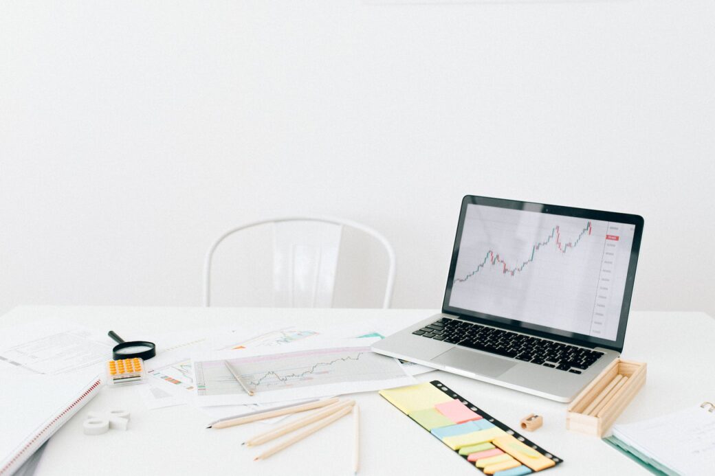 a laptop near documents and post it paper on white table