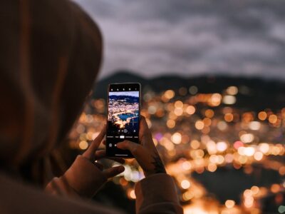 crop unrecognizable person taking photo of night city on smartphone