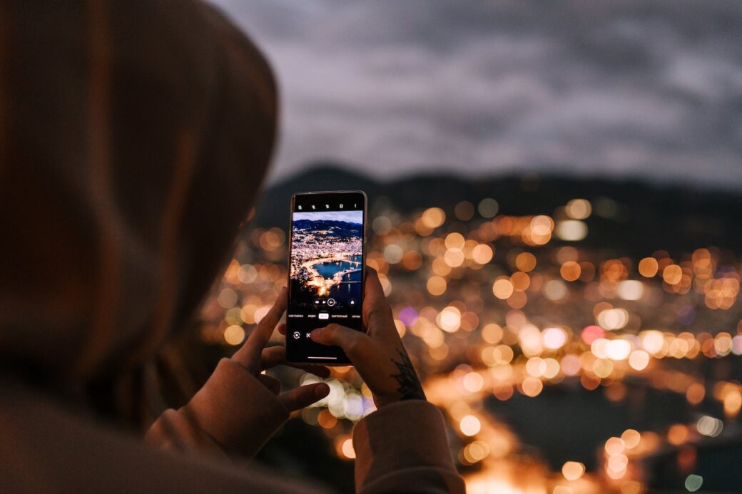 crop unrecognizable person taking photo of night city on smartphone