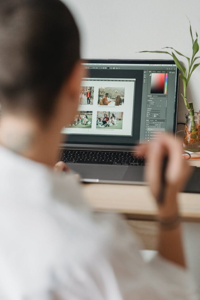 crop faceless photographer browsing laptop and choosing photos